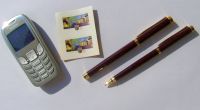 Imagefoto: Handy, Briefmarken und Kugelschreiber auf einem Tisch